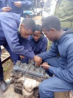 Automotive engineering trainees at work on an engine